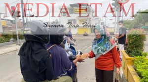 Seorang wartawan Berau tengah memberikan takjil kepada pengendara motor di Jalan APT Pranoto, Tanjung Redeb, pada Minggu (2/4/2023). [Christian / Mediaetam.com]