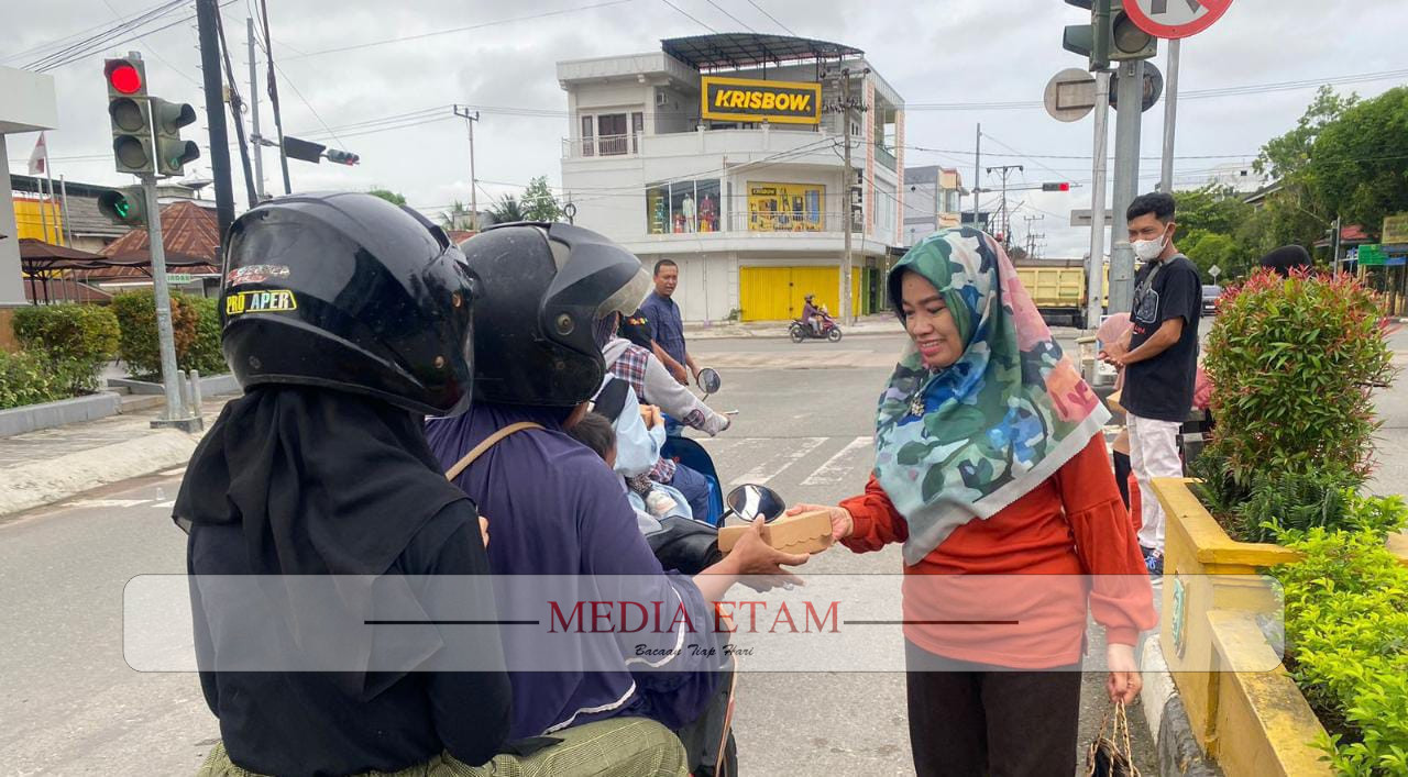 Seorang wartawan Berau tengah memberikan takjil kepada pengendara motor di Jalan APT Pranoto, Tanjung Redeb, pada Minggu (2/4/2023). [Christian / Mediaetam.com]