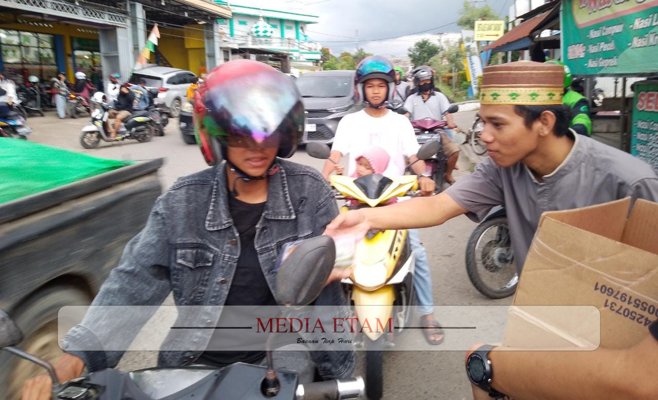 Salah satu pemuda Karang Taruna Gunung Panjang tengah memberikan paket takjil kepada masyarakat. [Christian / Mediaetam.com]