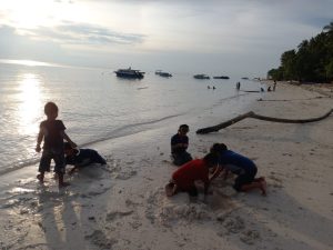 Anak-anak Maratua bermain di tepi pantai saat senja. (Noffi/Mediaetam.com)